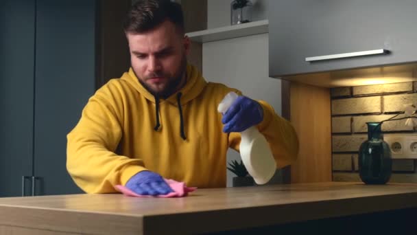 Kaukázusi férfi tisztít egy asztalt fertőtlenítő spray és törölköző visel kesztyű - Felvétel, videó