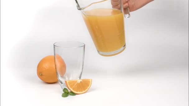 Mulher derramando suco de laranja em vidro no fundo branco - Filmagem, Vídeo