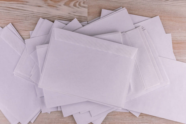 исходящая корреспонденция: несколько пустых белых конвертов на деревянном столе в офисе, низкий контраст - Фото, изображение
