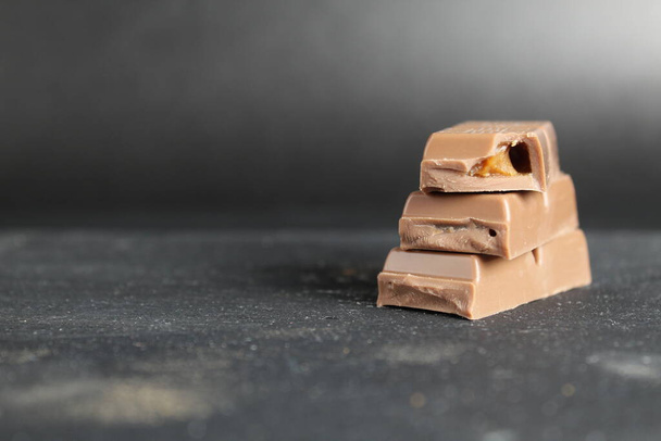 Nationale Milk Chocolate Day stockbeelden. Stapel chocolade met noten afbeeldingen. Chocolade geïsoleerd op een bruine achtergrond. Poster Dag van de Melkchocolade, 28 juli. Belangrijke dag. - Foto, afbeelding