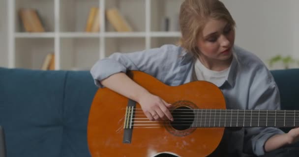 grać na gitarze w domu w weekend, hobby młodej uroczej damy, spędzać czas z ulubionym instrumentem muzycznym - Materiał filmowy, wideo