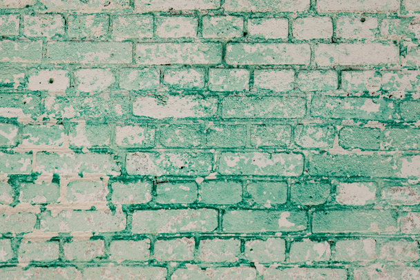 グランジの背景:白塗りと緑の塗料の残りの部分と色あせたレンガの壁 - 写真・画像