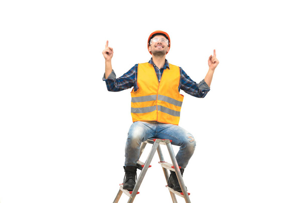O engenheiro feliz sentado na escada no fundo branco - Foto, Imagem