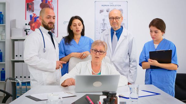 Lekarze w fartuchach laboratoryjnych pracujący w gabinecie szpitalnym omawiający objawy choroby - Zdjęcie, obraz