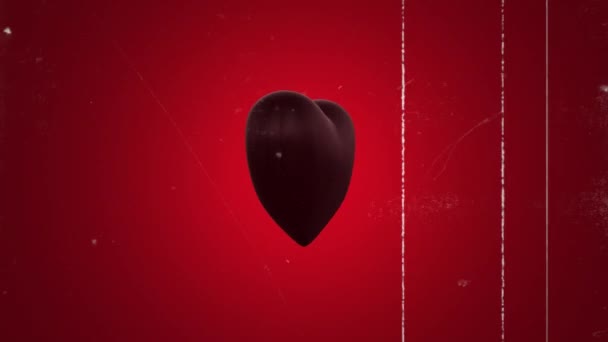 Animación 3D de corazón negro sobre fondo rojo. Ruido de película vieja y arañazos. Bucle. Concepto de San Valentín. - Metraje, vídeo