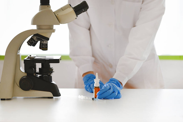 Médico em laboratório com microscópio e vacina inalatória SARS-CoV-2 - Foto, Imagem