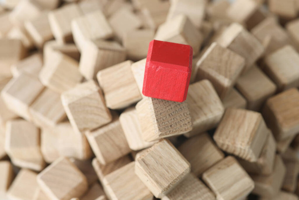 Cubos de madeira de cor bege no meio há cubo vermelho - Foto, Imagem