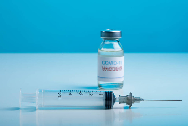 medisch concept: spuit en injectieflacon op blauwe achtergrond. vaccinatie. - Foto, afbeelding