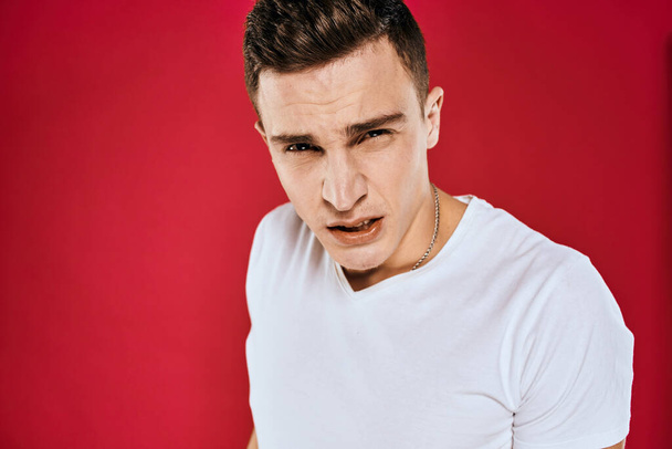 Emotional man white t-shirt displeased facial expression red isolated background cropped view - Foto, immagini
