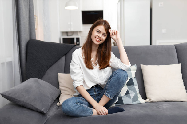 žena sedí na pohovce s polštáři pohodlný byt - Fotografie, Obrázek