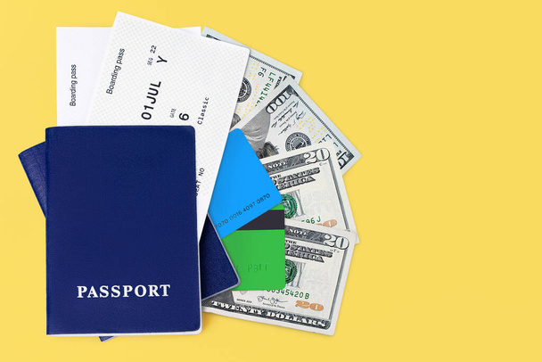 Blue passport, boarding pass, flight ticket, usa dollars, us cash money, american currency, credit cards on yellow background close seup top view, airplane travel, holidays, vacation, tourism, copy space - Фото, изображение
