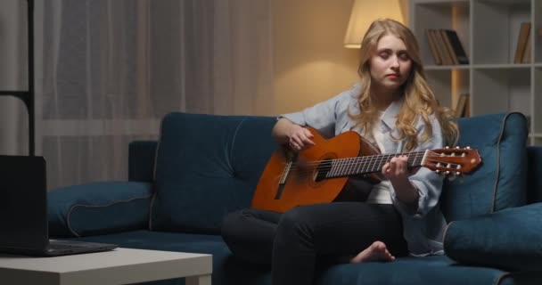 Lahjakas innoittamana nainen soittaa kitaraa kotona illalla, nauttia suosikki sävelmä, tehdä musiikkia - Materiaali, video