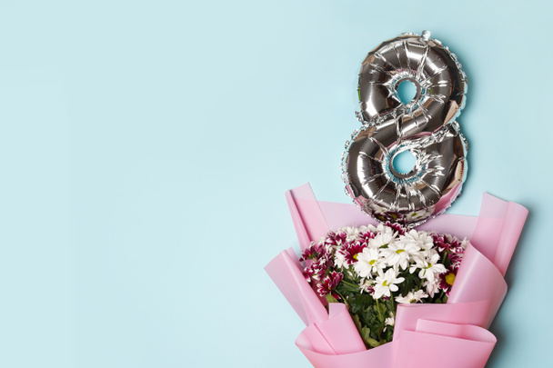8 silberne Zahl Ballon mit Blumenstrauß. blauer Hintergrund. Frauentag und 8. März. Grußkarte - Foto, Bild
