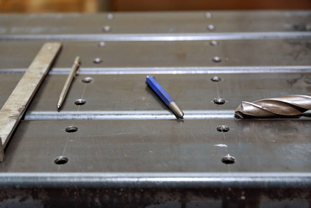 Markierung auf einer Metalloberfläche zum Bohren von Löchern mit einem Quadrat und einem Bremssattel. Hammer, Nagel, Punsch. - Foto, Bild