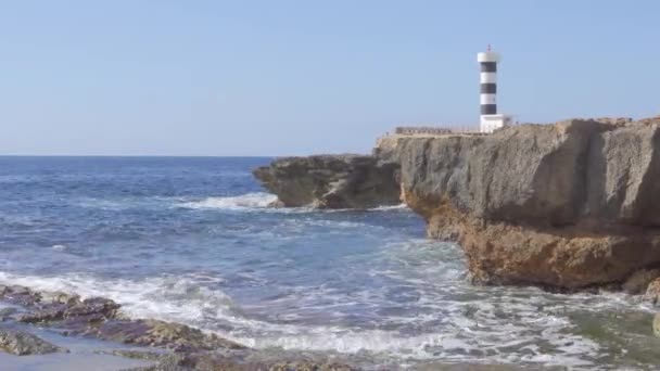 Maják Colonia de Sant Jordi za slunečného a klikatého dne. Středozemní moře na skalnatém pobřeží ostrova Mallorca, Španělsko - Záběry, video