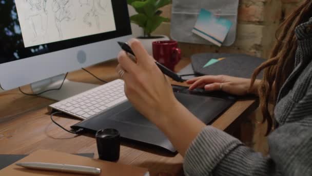Zwolnione zbliżenie nierozpoznawalnej kobiety pracującej jako grafik z rysunku domowego szkiców na tablecie graficznym za pomocą rysika - Materiał filmowy, wideo