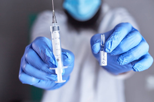 医師の手にCovid-19ワクチンとアンプル.予防接種の概念 - 写真・画像