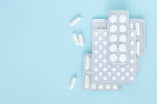 Confezioni di pillole bianche su sfondo blu, vista dall'alto. Vari farmaci, compresse, capsule medicinali. Inizio del trattamento, farmaci. Copia spazio. - Foto, immagini