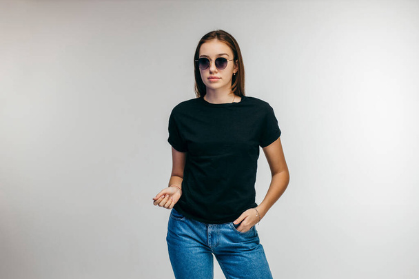 Menina elegante em óculos vestindo t-shirt preta posando em estúdio - Foto, Imagem