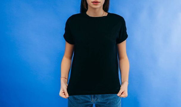 Stílusos lány visel fekete póló pózol stúdióban kék háttér - Fotó, kép