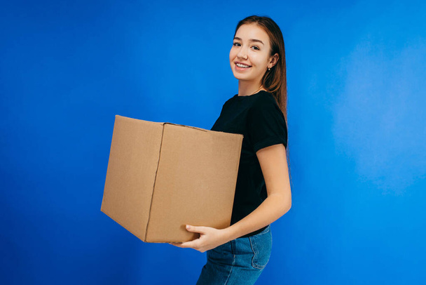 Young beautiful delivery lady carrying a blank cardboard box - Фото, зображення