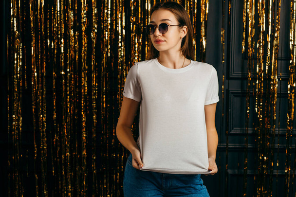 Menina elegante vestindo t-shirt branca e óculos de sol posando em estúdio - Foto, Imagem