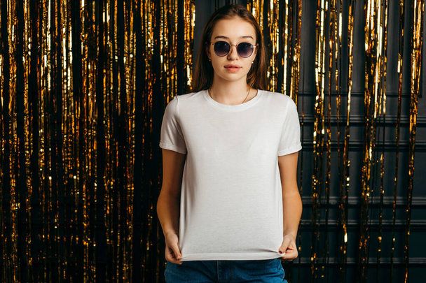 Menina elegante vestindo t-shirt branca e óculos de sol posando em estúdio - Foto, Imagem