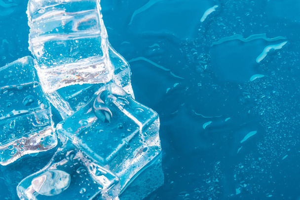 Erimiş buz küplerinin piramidi damlalarla. Buz küpleri ve su mavi arkaplana düşer. - Fotoğraf, Görsel