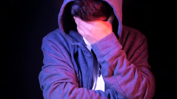 sad man in hood cover face with hands isolated in black. - Footage, Video