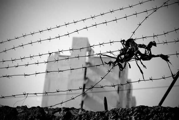 Barbed wire stretched over the wall with a multistory building seen far away in blur.  - Photo, Image