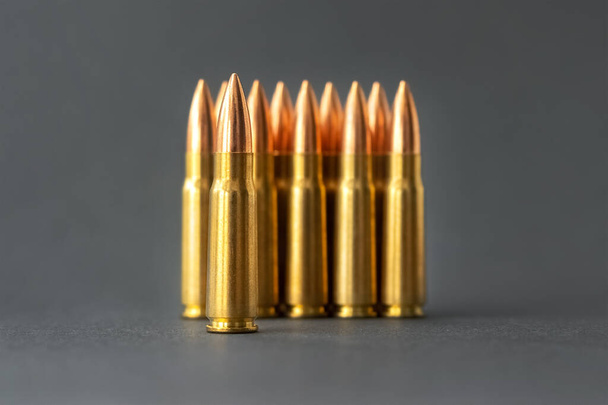 Balas sobre fondo gris. Cartuchos calibre 7.62 para el primer plano del rifle de asalto Kalashnikov. Enfoque selectivo en primer plano - Foto, imagen