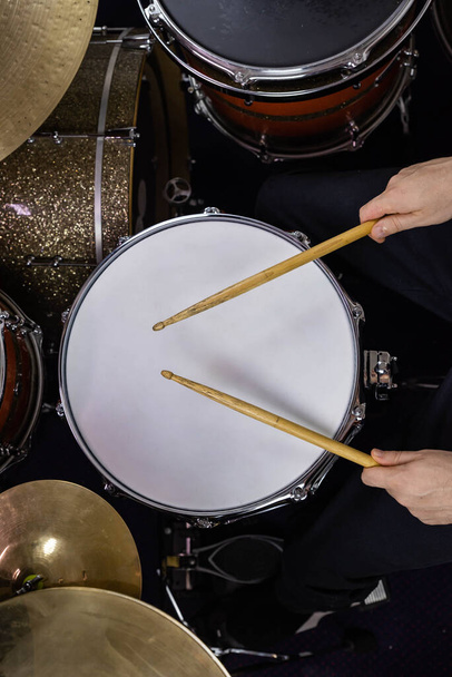 Professional drum set closeup. Man drummer with drumsticks playing drums and cymbals, on the live music rock concert or in recording studio    - Photo, Image