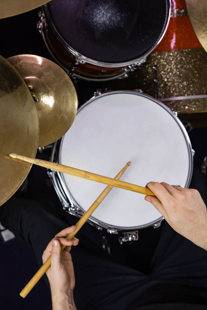 Professional drum set closeup. Man drummer with drumsticks playing drums and cymbals, on the live music rock concert or in recording studio    - Photo, image