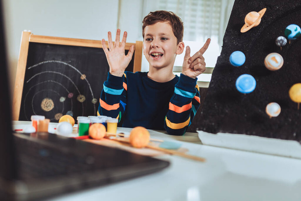 Ребенок представляет свой научный домашний проект - планеты нашей солнечной системы. Дистанционное обучение онлайн. - Фото, изображение
