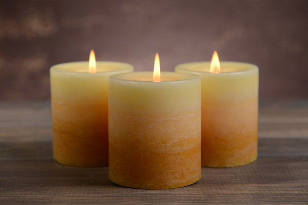 Beautiful candles on table on brown background - Fotoğraf, Görsel