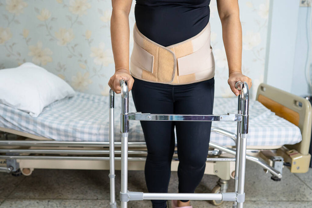 Ázsiai hölgy beteg visel hátfájás támogató öv ortopéd ágyéki Walker. - Fotó, kép