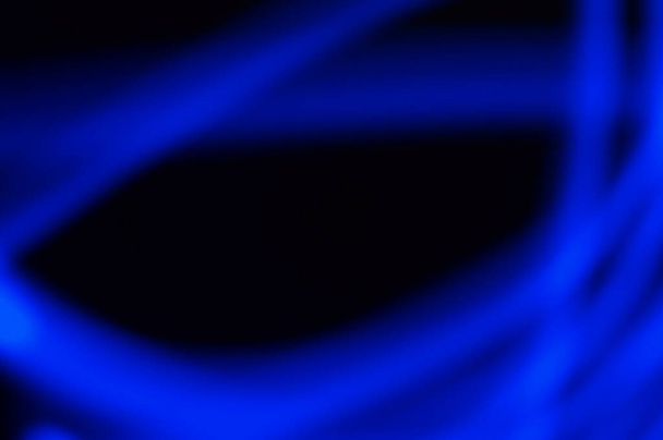 Modrá skvrna rozmazala neon na černém pozadí. Abstraktní čára s vysokým zvětšením. Pozadí pro písmo nebo grafiku. - Fotografie, Obrázek