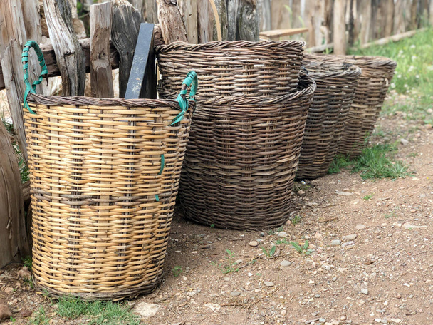 Puste wiklinowe kosze ustawione przed drewnianym płotem w wiosce - Zdjęcie, obraz
