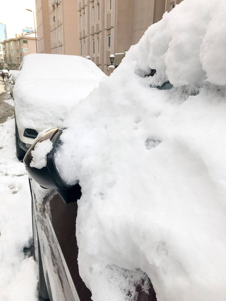 ряд припаркованных автомобилей под снегом на улице зимой - Фото, изображение