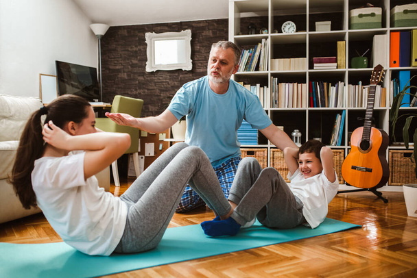 Здорове ранкове розтягування - чоловік з дітьми робить гімнастичні вправи вдома
 - Фото, зображення