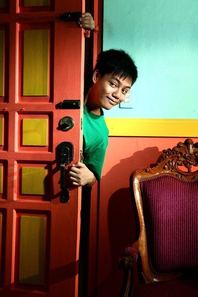 Jeune asiatique adolescent regarder et se faufiler dans un salon
 - Photo, image