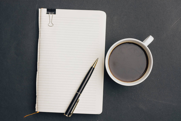 notebook com caneta no fundo escuro e xícara de café escritório vista superior - Foto, Imagem