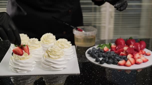 Chef pâtissier décore Anna Pavlovas gâteaux avec des fruits frais et des feuilles de menthe. - Séquence, vidéo