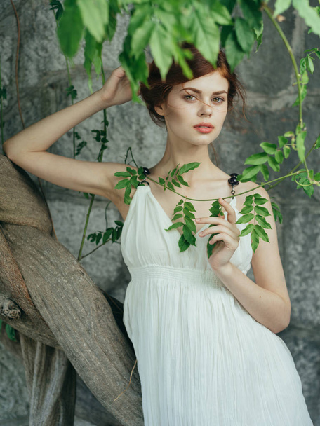 Pretty woman outdoors green leaves white dress summer walk - Foto, afbeelding