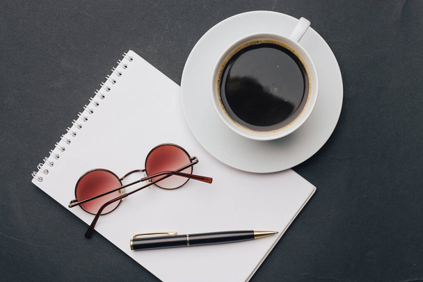 блокнот і кавова чашка офісна ручка і чорний стіл
 - Фото, зображення