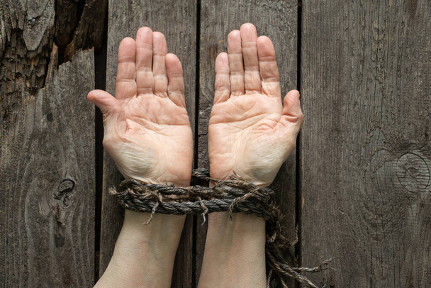 tied hands with rope of old woman on wooden table - Photo, Image
