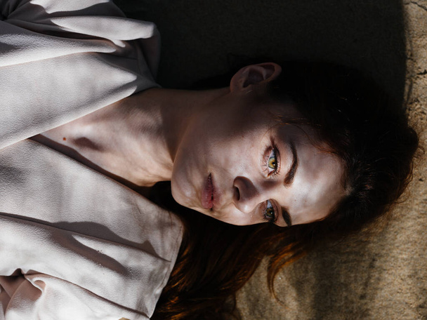 Beyaz önlüklü güzel kadın güneşin altında yerde yatıyor. - Fotoğraf, Görsel