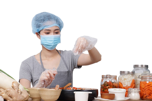 Asian woman sitting and making kimchi She wears a mask, gloves and a protective cap to keep food clean. White background. Korean fermented food concept made from vegetables. Clipping Path. isolated - Photo, Image
