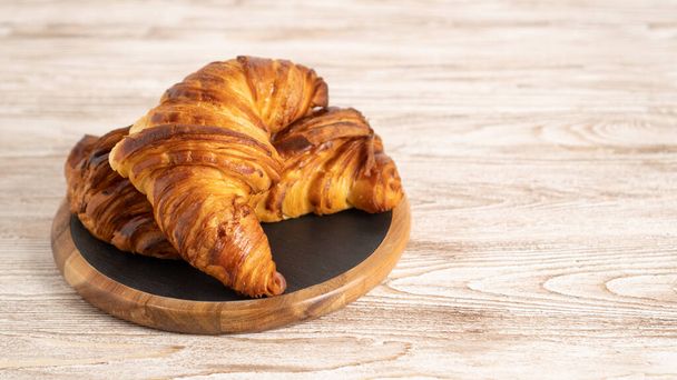 Croissants on black cutting board with copy space. Fresh croissant on a black slate background. Croissants pair - Photo, Image
