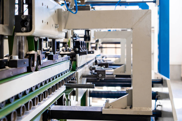 Μια βιομηχανική μηχανή κατασκευής φακέλων, κατασκευάζοντας φακέλους χαρτιού για διεθνή διανομή. Αυτόματες μηχανολογικές μηχανές για φακέλους χαρτιού μαζικής παραγωγής. - Φωτογραφία, εικόνα